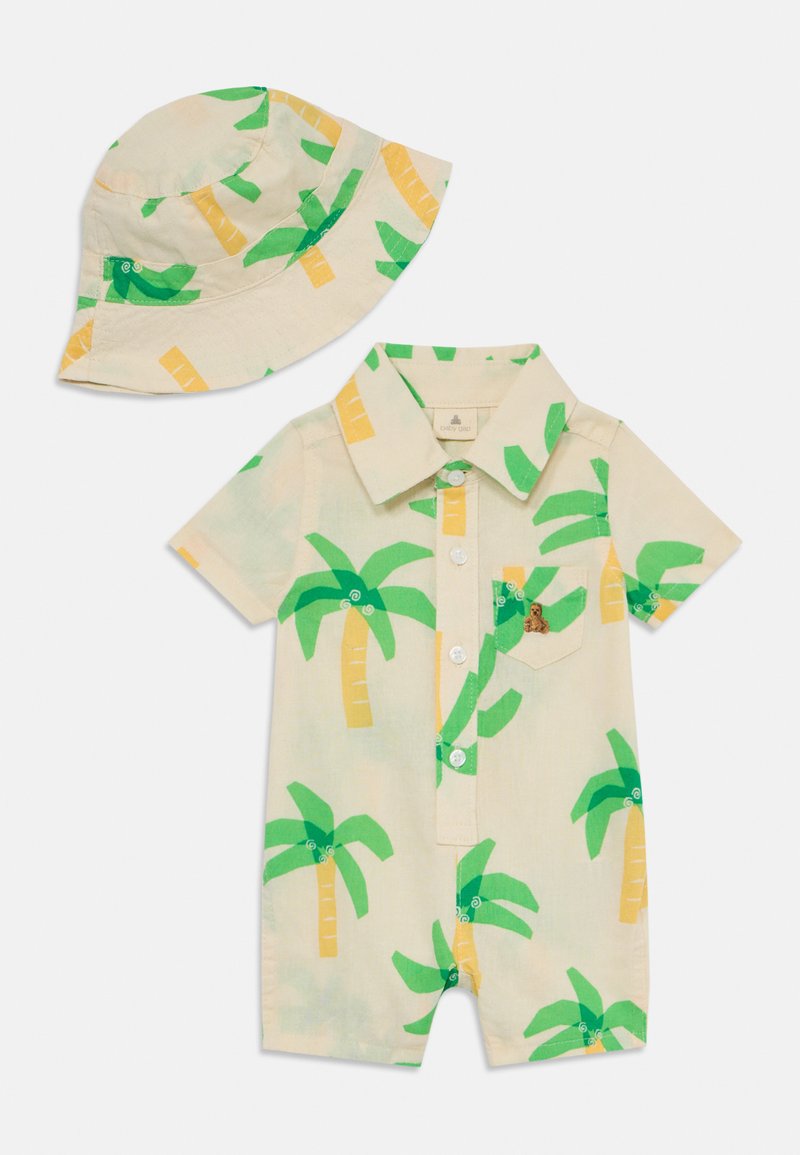 Kortärmad jumpsuit och matchande bucket-hatt i ljusbeige, med livfulla gröna palmer och en liten björn broderad på fickan.