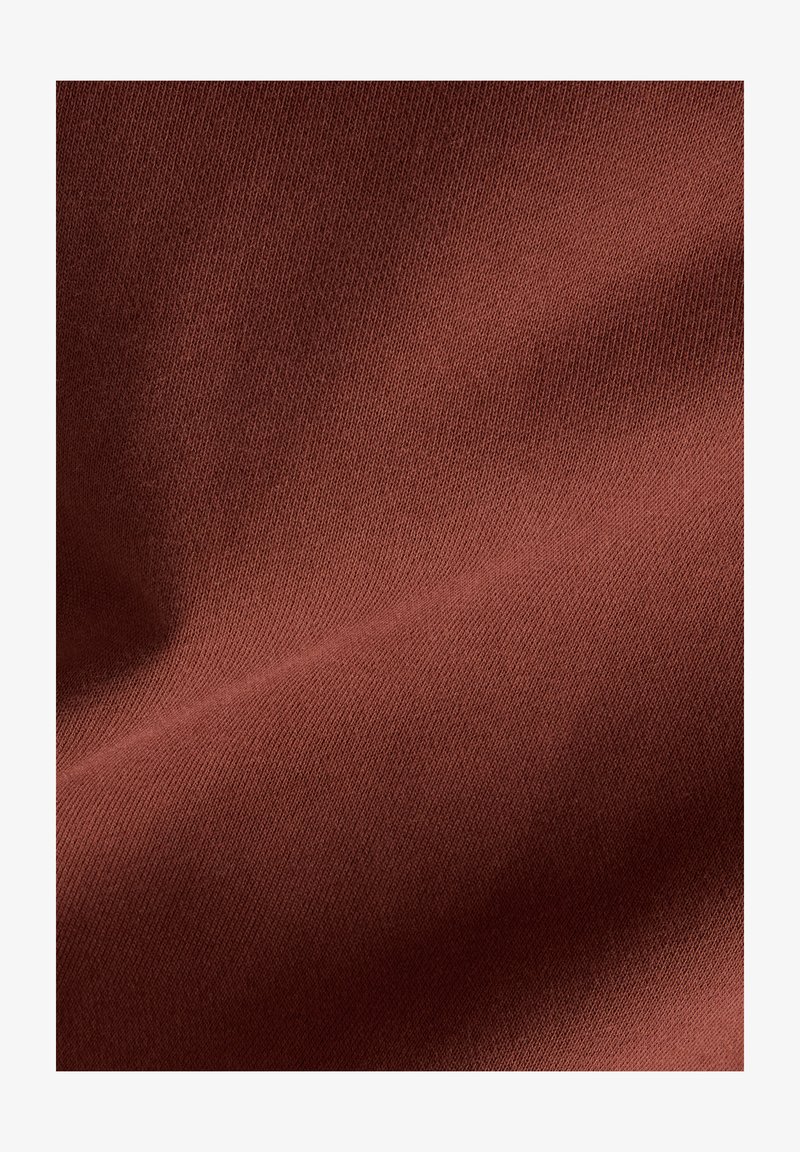 Brown stretch fabric with a smooth texture and a slight sheen, featuring a tight weave and light creases, indicating drape and flexibility.
