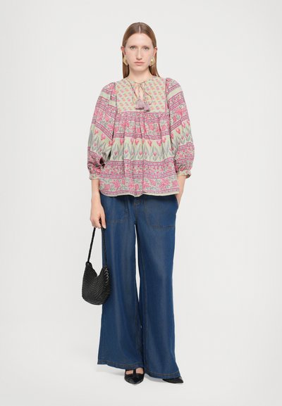 Floral patterned blouse in light colors with puffed sleeves and drawstring neck, paired with wide-leg blue denim pants and a black bag.
