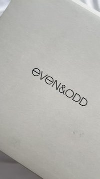 Bela pravokotna škatla z mat površino, na kateri je na sredini črno, moderno tipografijo zapisano ime znamke "even&ODD".