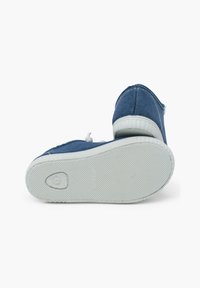 Adidași din pânză albastră, cu o talpă din cauciuc alb. Designul are un vârf rotunjit și cusături ușoare pe margini pentru un plus de detaliu.