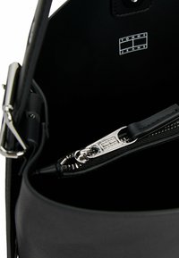 Zwart leren handtas interieur met zilveren rits, voorzien van een gladde textuur en een logo label. De ritsen trekhandeling is leeraccent.