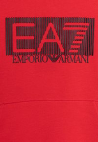 Felpa rossa con logo "EA7" a strisce verticali nere e scritta contrastante "EMPORIO ARMANI" al centro. Tessuto in misto cotone.