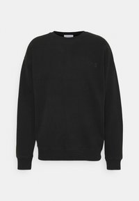 Svart sweatshirt i bomull med rund halsringning, långa ärmar, ribbade mudd och fåll, samt en liten relieflogotyp på bröstet.