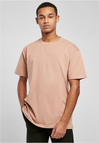 Lyserosa bomull T-skjorte med rund hals og korte ermer. Har en avslappet passform og minimalistisk design.