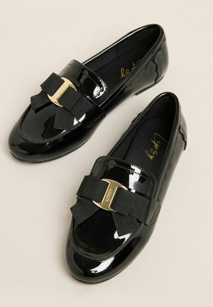 Mocasini din piele lacuită neagră, cu o fundă mare neagră și un detaliu de metal aurit. Textură fină, cu un design al vârfului rotunjit.