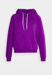Lila hoodie med en framficka, vita dragsnören och en liten grön logotyp. Tillverkad av mjukt tyg med ribbade muddar och nederkant.
