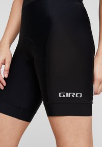 Svart sykkelshorts laget av elastisk materiale med en glatt tekstur. Har en Giro-logo i sølv på den nedre siden og en tettsittende design.