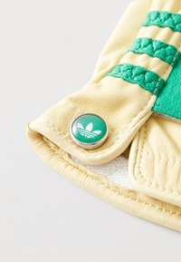 Yellow leather pouch with textured surface, featuring green striped accents and a green button with a white logo.