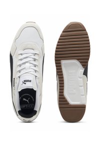 Valkoinen ja musta lenkkari, jossa on teksturoitu päällinen, pehmustettu nilkkaosa ja nauhat. Kumipohjassa on ruskea pito kuvio. Puma-logo kielellä.