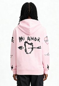 Felpa rosa con cappuccio e tasca frontale, stampe grafiche nere di cuori, frecce e teschi sulla schiena e sulle maniche, realizzata in tessuto morbido.