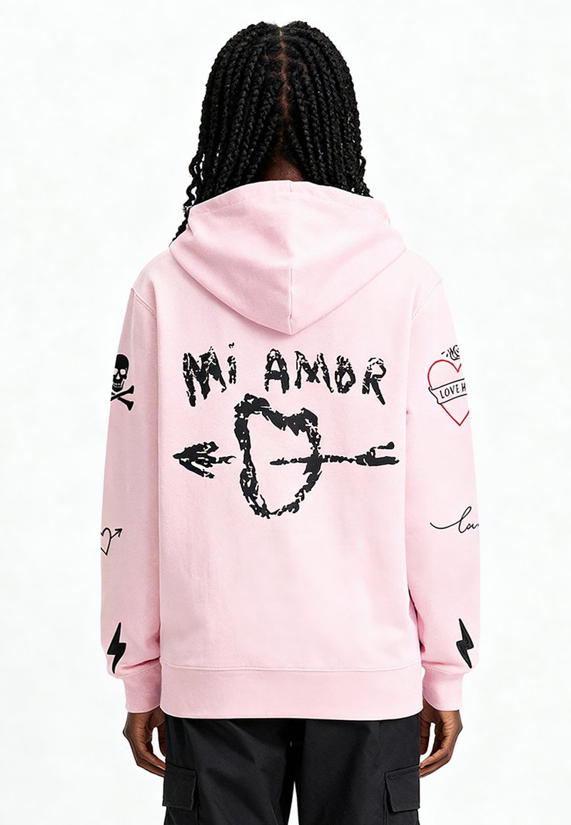 Felpa rosa con cappuccio e tasca frontale, stampe grafiche nere di cuori, frecce e teschi sulla schiena e sulle maniche, realizzata in tessuto morbido.