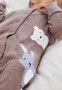 Brauner Baby-Overall aus weichem Stoff, mit gesticktem weißen Bären und grauem Hasen auf der Vorderseite, mit Druckknöpfen an der Seite.