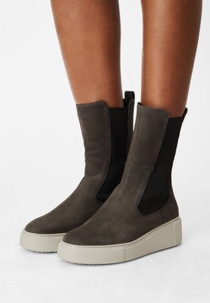 Bottes chevilles en daim gris avec panneaux élastiques sur les côtés, bouts arrondis et semelle plateforme blanche épaisse pour plus de hauteur.