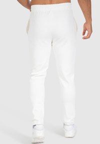 Witte joggpantalons met een gladde katoenstructuur, voorzien van een geribde elastische tailleband en zijzakken. Het ontwerp is aansluitend bij de enkels.