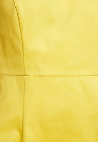 Zachte gele stof met zichtbare verticale en horizontale naden die rechthoekige panelen vormen.