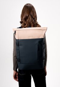 Černý a světle růžový vod�ěodolný batoh s nastavitelnými popruhy, designem s rolovacím víkem, zipovou kapsou a bočními úložnými oddíly.