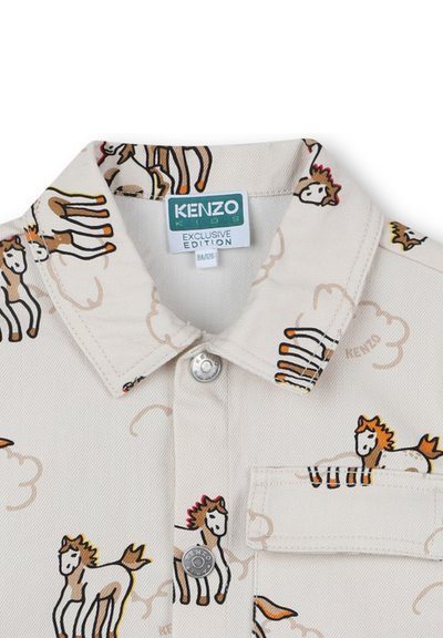 Beige kinderpolo met bruine paardafdrukken, voorzak, drukknoopsluiting en een Kenzo Kids Exclusive Edition-label aan de binnenkant van de kraag.