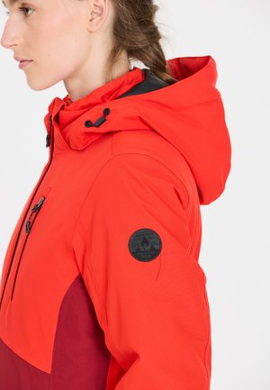 Red and burgundy jacket with a hood, featuring a front zipper pocket and a black logo patch on the sleeve. Smooth texture and sporty design.
