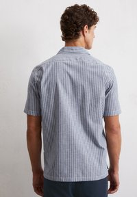 Short-sleeve shirt in light blue with white vertical stripes. Features a collar and a relaxed fit, made from lightweight fabric.