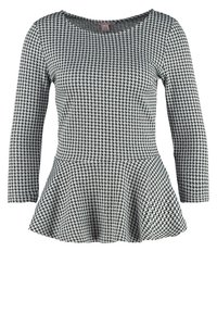 Black and white houndstooth patterned top with a peplum design. Features long sleeves and a round neckline, made from smooth fabric.