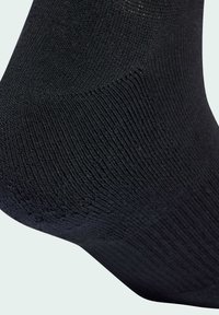 Czarna skarpeta o gładkiej, dzianinowej fakturze; posiada wzmocnione piętę i palce. Prosty design bez wzorów i ozdób.