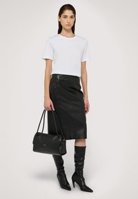 Vit T-shirt, svart pennkjol i läder, svarta knähöga stiletto-stövlar och en svart handväska med slät yta och subtil gulddetalj.