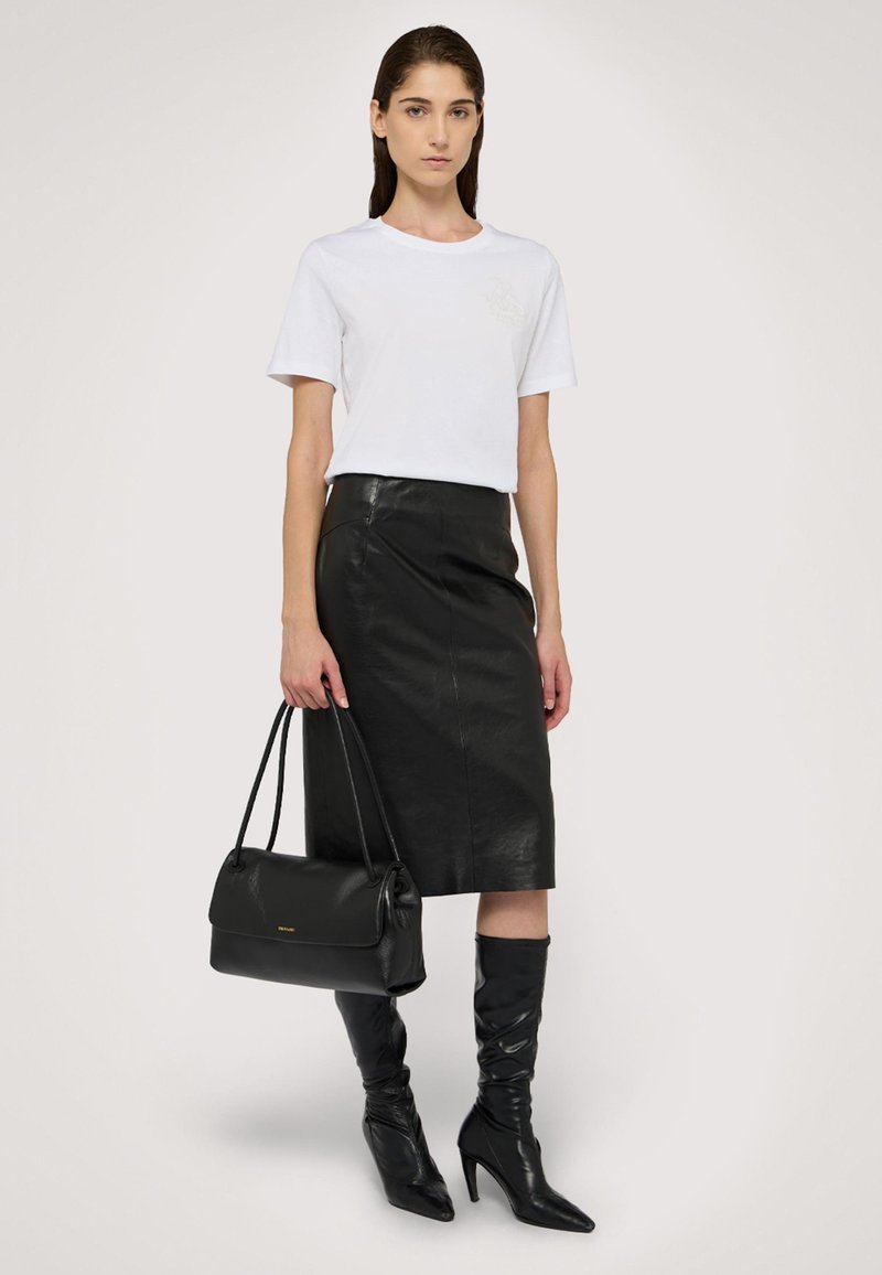 Vit T-shirt, svart pennkjol i läder, svarta knähöga stiletto-stövlar och en svart handväska med slät yta och subtil gulddetalj.