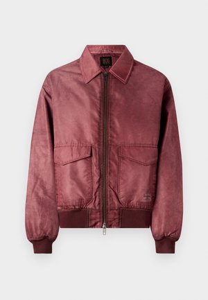 Veste bombardier bordeaux avec fermeture éclair à l'avant, deux poches poitrine, poignets côtelés et texture lisse semblable à du satin. Présente un design classique avec col.