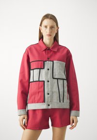 Red and grey jacket with geometric patterns, featuring black accents, button closure, and a relaxed fit. Paired with matching shorts.
