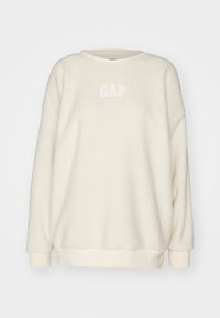 Kremowy polarowy sweter z okrągłym dekoltem, z uniesionym białym logo "GAP", ściągaczami przy mankietach oraz na dole.
