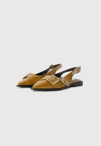 Brown patent leather slingback shoes with pointed toe, wide strap featuring large silver buckles, and a low black heel.