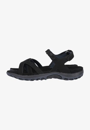 Sandales noires avec une semelle intérieure texturée, des sangles croisées et une fermeture réglable en velcro, dotées d'une semelle en caoutchouc durable et flexible.