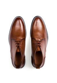 Brune lædersko med en glat finish, rundet snude, snørebånd med fire huller og en kontrasterende sort gummisål.