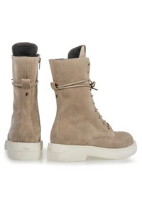 Stivali in suede beige con lacci e design alto alla caviglia, dotati di una resistente suola in gomma bianca, chiusura con zip e accenti hardware minimalisti.