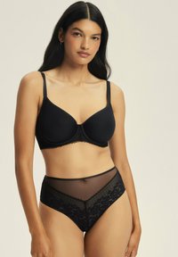 Czarny stanik z gładkimi miseczkami i koronkowym wykończeniem, w połączeniu z czarnymi majtkami o wysokim stanie, wykonanymi z przezroczystego materiału z kwiatowymi koronkowymi detalami.