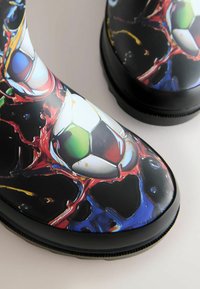 Black rubber rain boots featuring a glossy surface with a colorful soccer ball print and abstract red and blue splashes.
