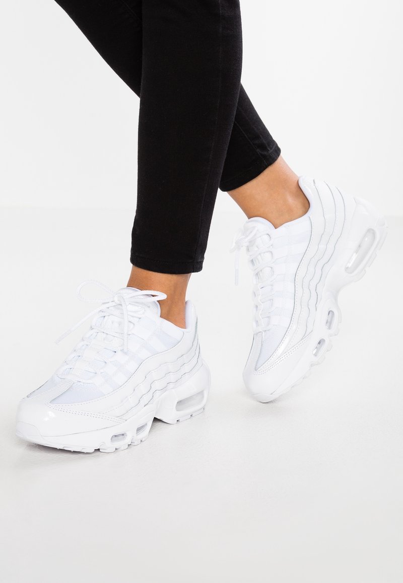 Sneaker bianche con una tomaia in mesh texturizzato, pannelli lisci e ammortizzazione d'aria visibile nella suola. I lacci sono allacciati, con un design sportivo.