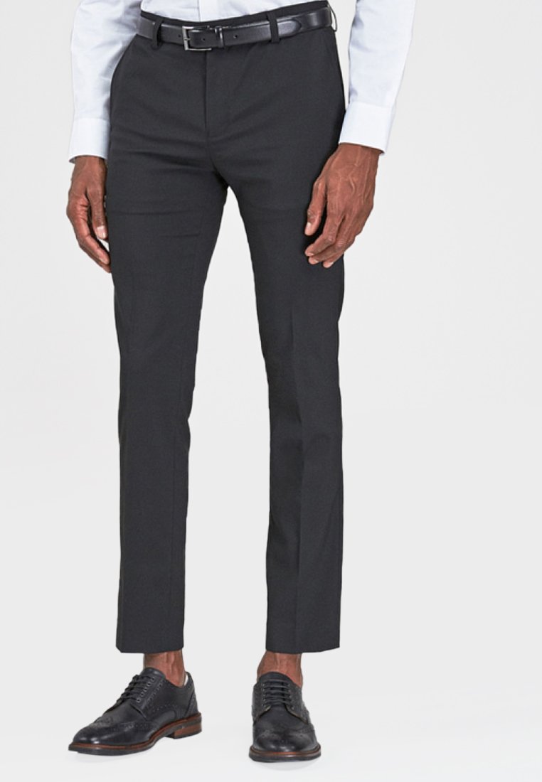 Pantalones negros ajustados, de corte slim, con una textura suave; combinados con zapatos negros con cordones y un cinturón negro; utilizados con una camisa de color azul claro.