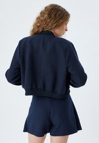 Marineblaue, strukturierte Bomberjacke mit gerippten Bündchen, im verkürzten Design und mit glatter Oberfläche, kombiniert mit passenden Shorts.