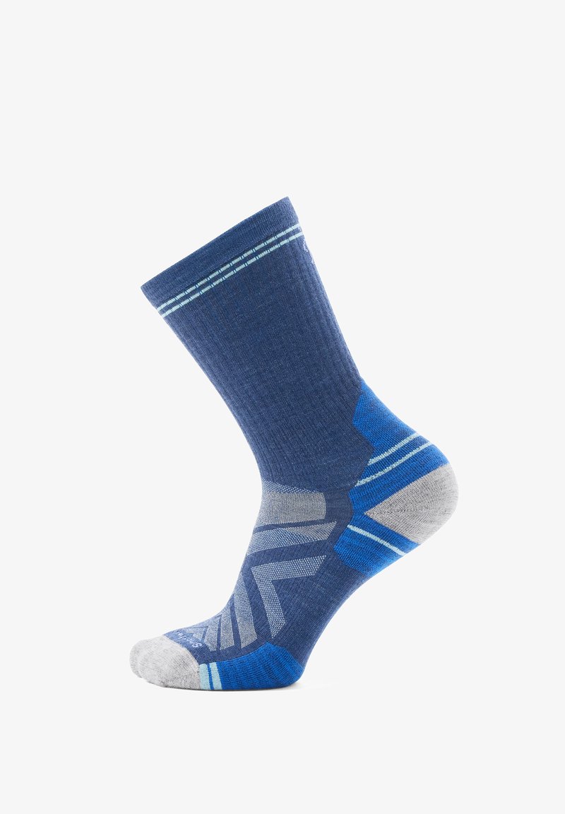 Sininen sukka, jossa on harmaita ja vaaleansinisiä yksityiskohtia, koristeltu raidallisella varrella, geometrisella kuviolaatalla sekä vahvistetuilla kantapää- ja varvasalueilla.