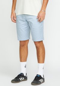 Light blue shorts with a smooth texture, featuring side pockets and belt loops, paired with black sneakers and white socks.