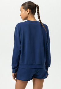 Marineblauwe sweatshirt met een ronde halslijn en geribde boorden, gecombineerd met bijpassende shorts. Gladde textuur en een losse pasvorm.