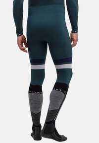 Thermische Sportleggings in dunkler Tönung mit kontrastierenden hellen und marineblauen horizontalen Streifen, kombiniert mit grauen, gemusterten knielangen Socken.