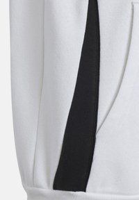 Sweatshirt blanc avec un panneau latéral noir uni. Le tissu a une texture douce et des accents côtelés près de la taille et des poches.