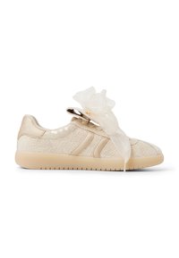 Beżowe sneakersy z koronkowym wykończeniem, satynowymi akcentami, cekinami i dużą, przezroczystą wstążką zawiązaną w kokardę na białym tle.