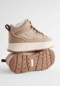 Sneakers in stile Alert di colore beige chiaro, con una combinazione di rete e suede, fodera morbida, occhielli metallici e una suola in gomma testurizzata.