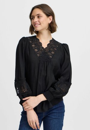 Blouse noire avec un col en V orné de détails en dentelle complexe, manches bouffantes avec finition en dentelle, et coupe décontractée. Tissu doux et léger.