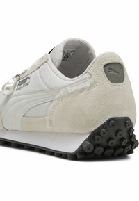 Baskets Puma Easy Rider en daim blanc et beige avec des superpositions texturées. Dotées d'une semelle extérieure en caoutchouc avec des crampons proéminents pour une meilleure adhérence.