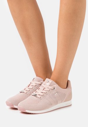 Zapatillas deportivas de color rosa claro con parte superior de punto, diseño de cordones, acentos texturizados y suela blanca que presenta un sutil logo de la marca.